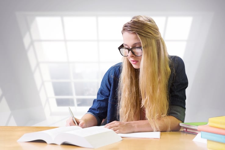 Student studying in the library against room with large window showing city.jpeg