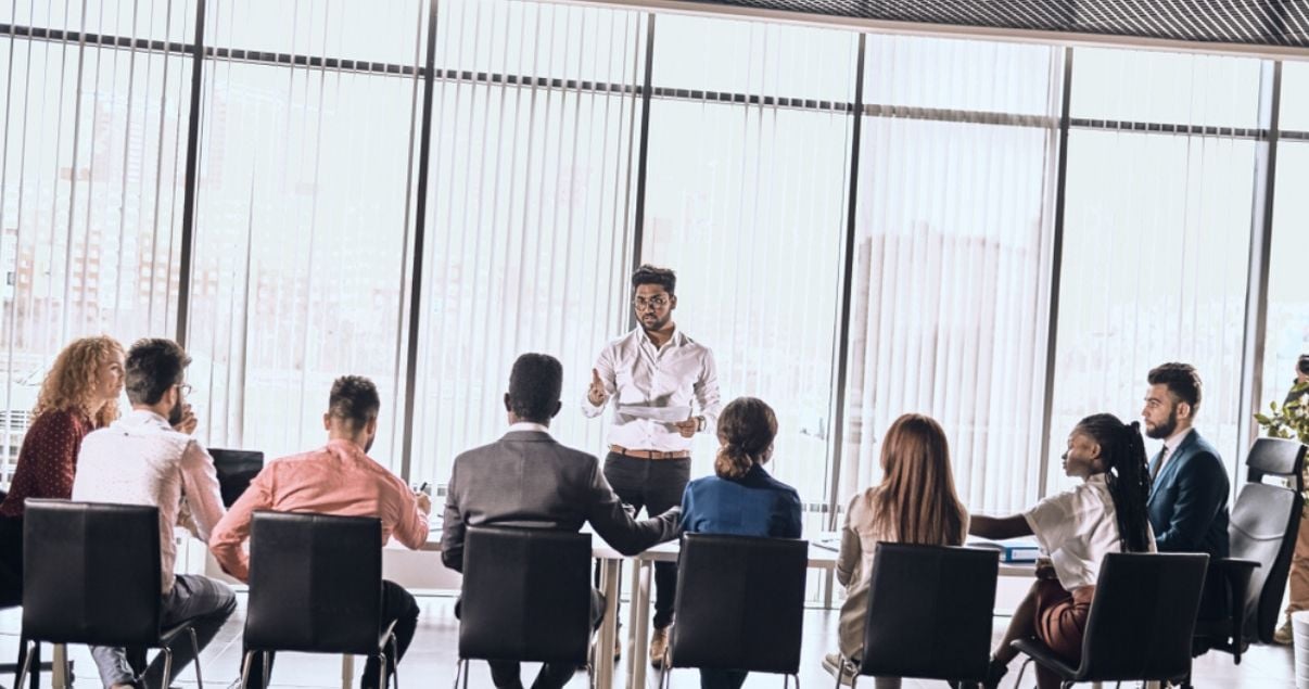 Ejecutivos en un programa de capacitación en inglés frente a un profesor en una mesa de reuniones