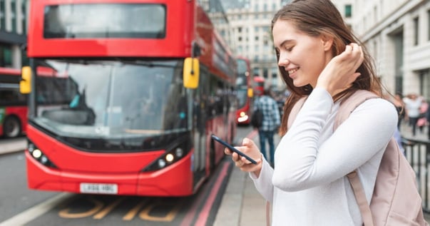 ピンクのリュックを背負った若い学生が、携帯電話で英語で道を探しています