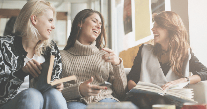 3 amigas con abrigos leyendo libros en ingles en una cafeteria en invierno