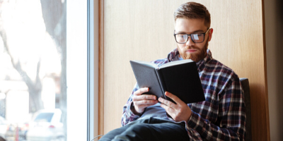 hombre con lentes leyendo un libro para hablar inglés con fluidez