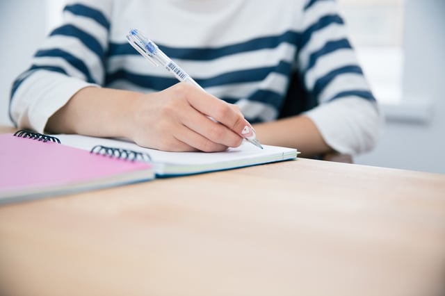 CLoseup portrait of a woman writing in notepad at office.jpeg