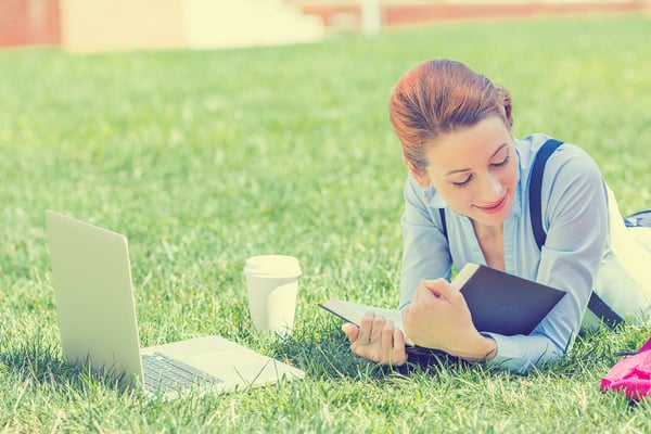 Student studying in park. Joyful happy young girl student sitting reading book outside on university campus or park. Education concept. Positive face expression-1