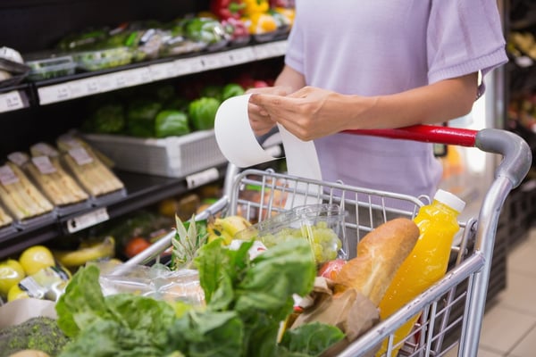 Woman reading her shopping list while pushing a shopping trolley