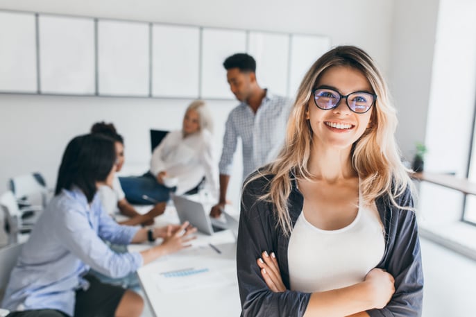 blonde-female-executive-posing-with-smile-and-arms-crossed-during-brainstorm-with-managers-indoor-portrait-of-european-student-spending-time-in-hall-with-asian-and-african-friends